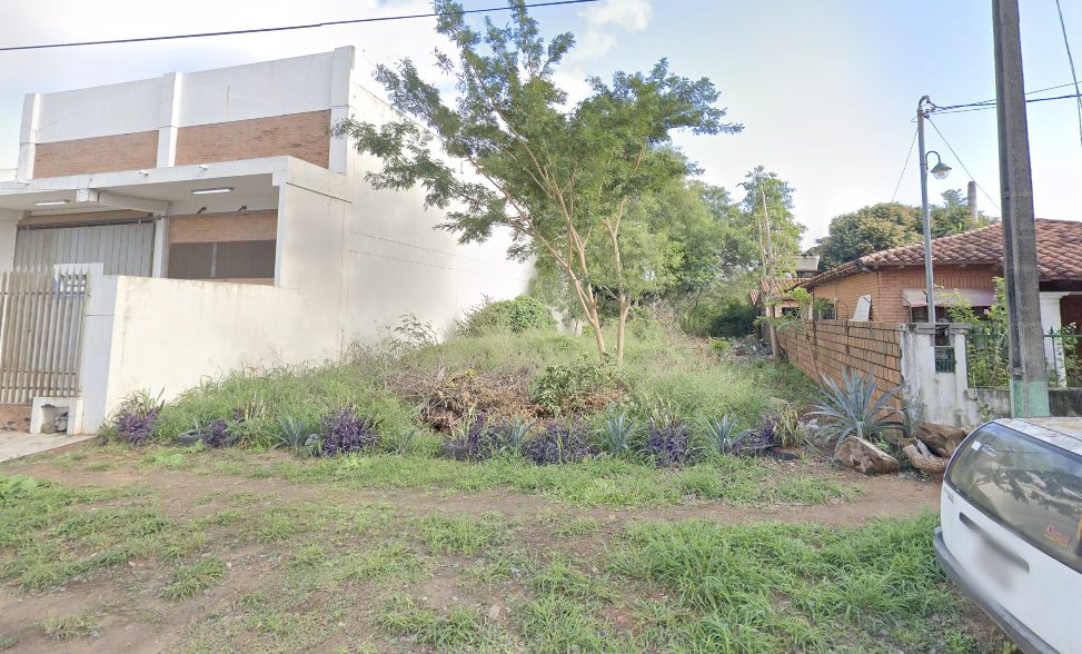 Terreno de Lumen Studios antes de la obra, con vegetación, entre un galpón de ladrillo y una casa de tejas